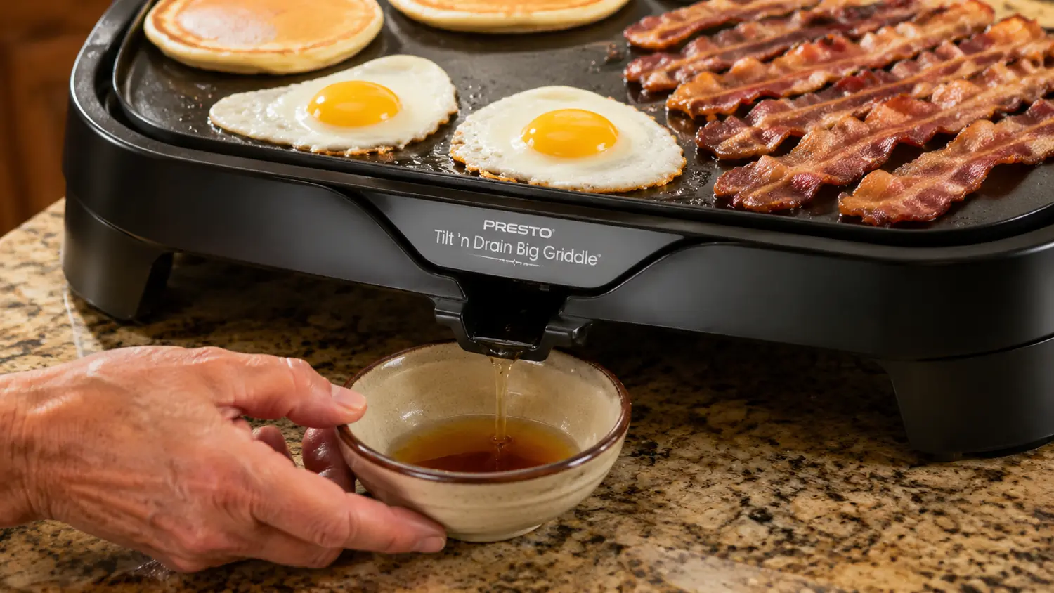 The Presto griddle's grease drip spout draining into a small catch cup at the counter edge