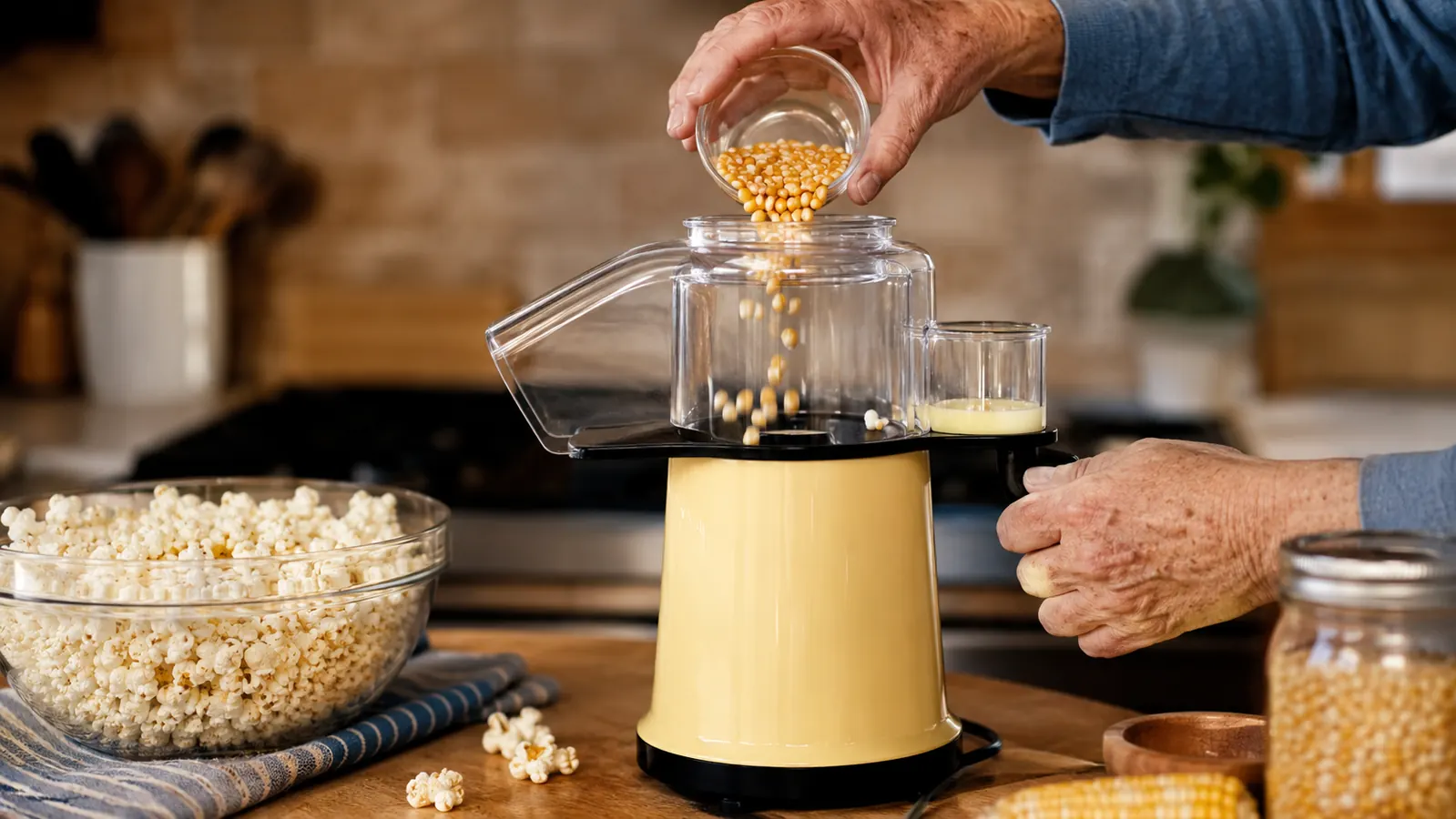 Hand pouring popcorn kernels into the built-in measuring cup on top of the Presto Poplite popper
